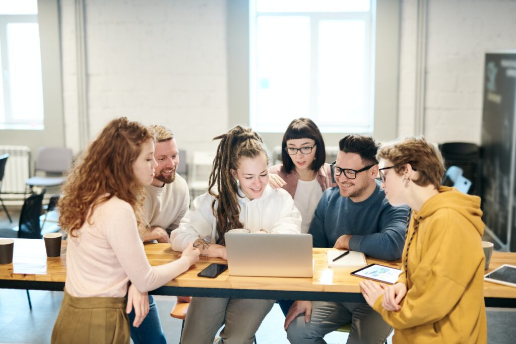 A group of employees looking at a laptop with an open internal social network.